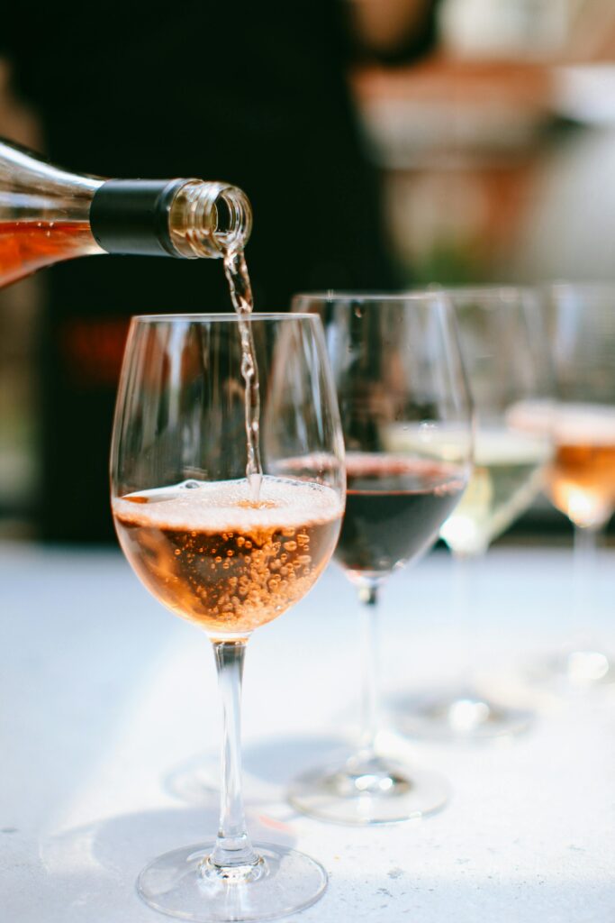Close-up of wine glasses with rosé being poured, showcasing bubbles and reflections.