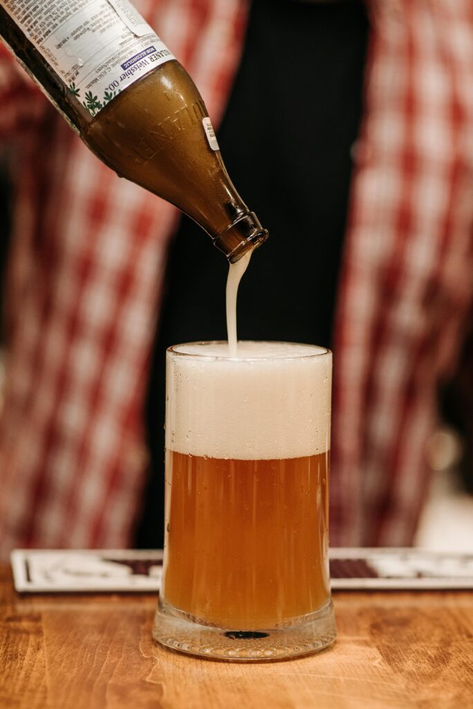 Close-up shot of a beer being poured into a glass with a rich foamy head.