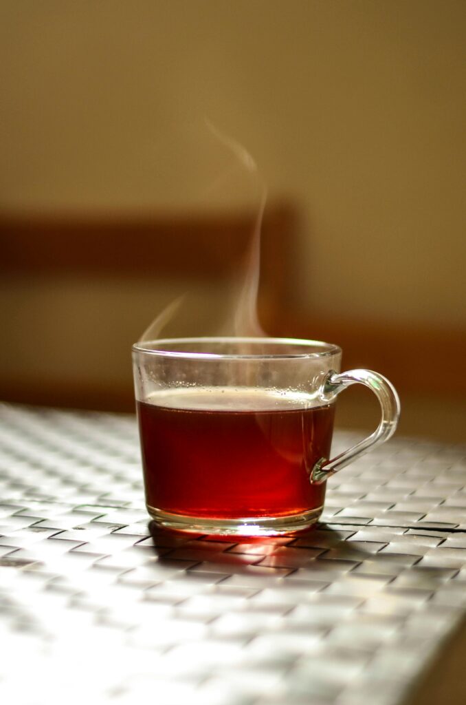 A steaming glass of tea adds warmth to an indoor setting, captured in a modern style.